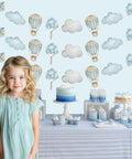 Blue Hot Air Balloon Banner Set For Baby Shower And Birthday Party Adventure Awaits Garland With Clouds And Balloons Three Piece Hanging Decor Travel Theme Party Supplies Totally Fun over dessert table with cupcakes and cake, young girl in dress standing in front.