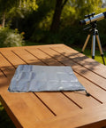 Silver 420D Oxford Telescope Cover For Outdoor Use With Reflective Heat Defense on wooden table next to telescope.