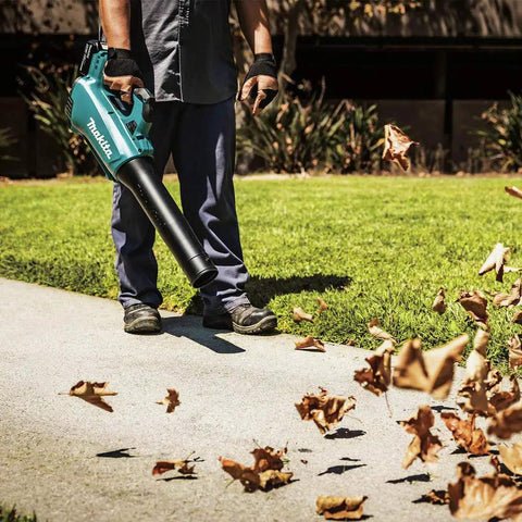 Man using Powerful 18V Cordless Blower Kit With 459 CFM 116 MPH Brushless Motor blowing leaves on a grass field