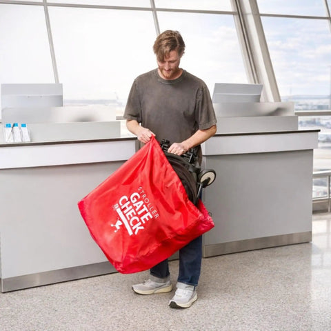 Man using Gate Check Travel Bag For Compact Fold Strollers With Built In AirTag Holder Red Protects Your Stroller From Dirt And Damage While Flying Fits Most Single Strollers Airport Travel Essential at airport check-in