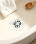 Hair Drain Stickers 100Pcs Disposable Self Adhesive on a shower floor with hair, featuring a dense mesh design.