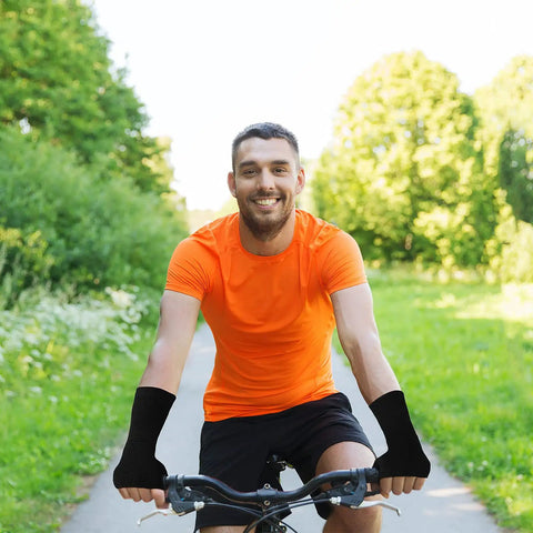 Cyclist wearing set of four unisex fingerless compression gloves with wrist support for sports thumb protection in black