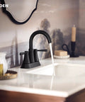 Ronan Matte Black Two-Handle 4-Inch Centerset Modern Bathroom Faucet With Push-Down Drain installed on a sink.