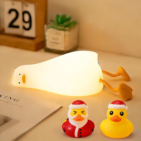 Squishy Silicone Rubber Duck Night Light For Nursery Baby And Kids Dimmable Rechargeable Touch Led Lamp BPA Free Non Toxic Bedside Light For Breastfeeding Shatterproof Safe Cozy Glow glowing on a table with two small duck figures.