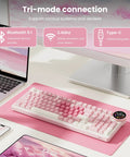 Top Shelf Wireless Mechanical Keyboard With Smart Screen And Rotary Knob, Gasket Mounted Hot Swap Tactile Switches Pre Lubed For Silky Typing, Triple Mode Bluetooth And Usb Setup, Compact 96 Percent Layout That Goes Hard For Gaming on a pink desk with a laptop.