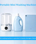 Rechargeable Mini Portable Washing Machine For Underwear And Baby Clothes Compact Travel Laundry Cleaner Lightweight Delicate Cycle Perfect For Dorms Hotels And Road Trips Game Changer next to laundry detergent bottle and iPad for size comparison.