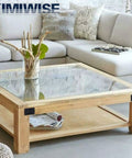 Stylish square coffee table with glass top and wooden base, adorned with decorative plants, in a cozy living room.