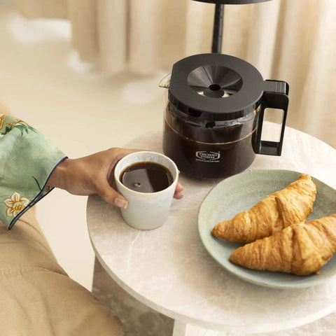 Breakfast table with 1.25L Glass Carafe for KBG Brewers, Clear Black Version, coffee, and croissants.