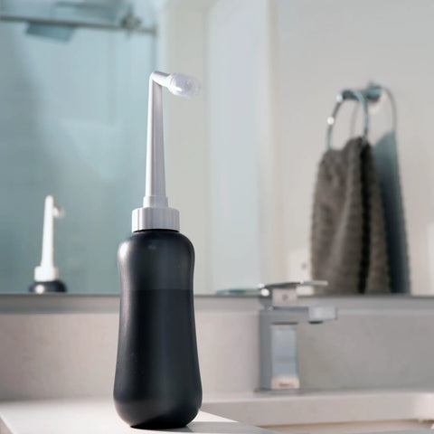 MicroJet MJ 450 Portable Bidet And Peri Bottle Sprayer For Travel on bathroom counter with angled nozzle.