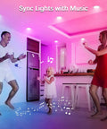 Family dancing in a kitchen with 10 Pack 9W Color Changing LED Recessed Lights 4 Inch Dimmable Ceiling Retrofit Smart Lights With Bluetooth Mesh Control 70W Equivalent Easy Install Compatible With Alexa And Google Assistant, syncing colorful lights with music.
