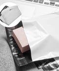 100 Pack White Poly Mailer Bags Thickened Lightweight Envelopes With Strong Adhesive Seal For Clothing Shipping And Small Business Mailers Leakproof Rainproof Quick Seal Design with package inside, shown on table