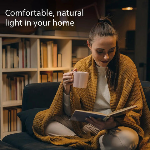 Woman reading in living room under LED A19 60W Equivalent Soft White Bulbs 2700K 800 Lumen 8 Pack Dimmable