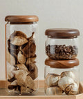 Four Piece Glass Storage Jars With Airtight Wooden Lids Wide Mouth Canister Set For Coffee Beans Sugar Tea Kitchen Pantry Upgrade Built Different Design Keeps Goods Fresh As Heck Super Easy Cleanup with dried fruits and coffee beans.
