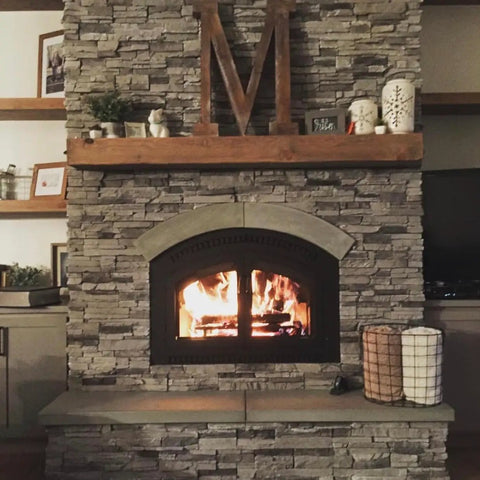 Cozy fireplace with stone surround and wooden mantel, featuring glowing flames and decorative accents in a warm setting.