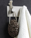 Heavy Duty Stainless Steel Wall Mounted Hooks Featuring Super Strong Self Adhesive Tape For Bathroom Towels Coats And Home Organization No Drill Hassle Rust Proof Daily Setup with white towel and lava stone.