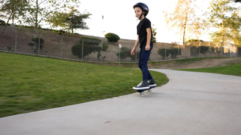 Rider using RipStik Ripster Caster Board For Narrow Stance Riders 9 Inch Blue With 360 Degree Trucks on a park path.
