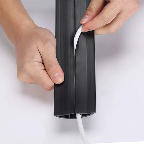 Hands inserting a cable into a 6 Ft Floor Cord Cover Cable Protector for Office Home and Outdoor Use Heavy Duty PVC Wire Channel Hider