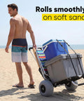 Beach Wagon With 12 Inch Massive Wheels For Sand And All Terrain Hauling, carrying coolers on a beach by a person