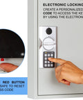 Person programming electronic lock on 110 Key Steel Safe Cabinet With Digital Lock For Wall Mount Key Storage Box, light gray finish.