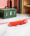 Premium Heavy Duty Recoil Air Hose For Air Compressor Killer Leak Proof System With Strong Quick Attach Connectors Built To Be Real Tough For Serious Daily Use In Auto Shops Or Home Garage Spaces Flows Great For Paint Guns Nailers With Zero Woes. orange coiled air hose with metal quick-connect fittings on garage floor