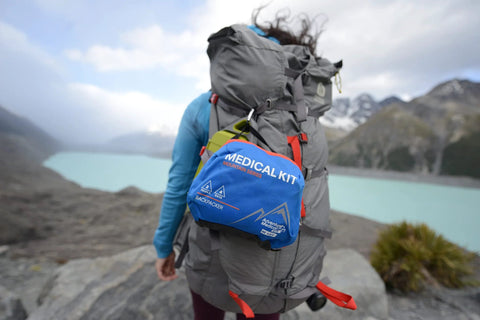 Adventure Medical Kits Mountain Series Backpacker Medical Kit blue/orange attached to a gray hiking backpack, side view