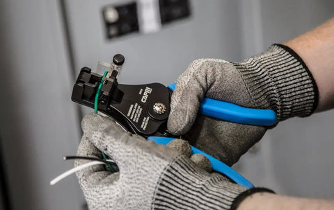 Precision Pro Grade Wire Stripper For 22 To 8 AWG Wires With Adjustable Setting, held by gloved hands in a workshop setting.