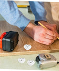 Person using a pencil to mark wood surface with Eight Piece Stainless Steel Self Adhesive Caster Wheels With Smooth Ball Bearings For Effortless Furniture Relocation And Heavy Duty Storage Box Glide Conversion Today.