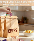 Slick 10 Pack Colorful Metal Chip Bag Clips With Rubber Finger Guards And Heavy Spring Steel Design sealing bags of chips on a kitchen counter.
