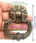 Close-up of a vintage brass ring pull handle with dragon head motifs, hand-held, showing detailed engravings and pumpkin style disk base.