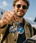 Person holding keychains with globe and rocket designs in front of airplane.