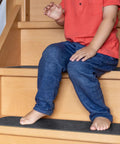 Child sitting on steps with dark grey Non Slip Stair Treads Carpet 8x30 Inches Pack Of 15 Peel And Stick Self Adhesive Step Mats