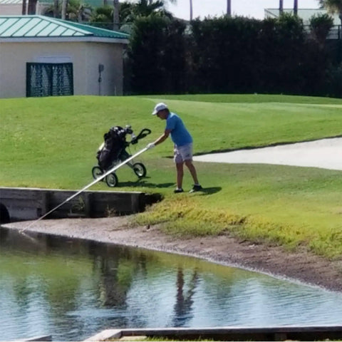 Golfer using 18 Foot Telescopic Golf Ball Retriever With Lightweight Aluminum Shaft Stainless Cup And Locking Hinged Design For Easy Water Pond Mud And Rough Retrieval No Fuss Pickups Every Time by a water hazard