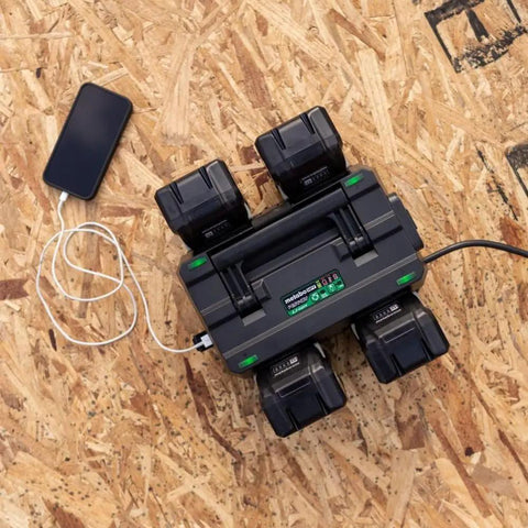 Overhead view of 4 Port Pro Grade Battery Charger for 18V and 36V lithium ion tools on plywood surface, charging batteries and phone.