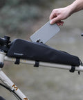 Extra Long 1.6L Top Tube Bag With Strap Mount on bike, black, sleek design, person placing phone inside zippered waterproof frame bag