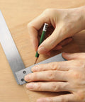 Suwimut machinist square set, steel L-shaped 90-degree ruler in use to mark wood; hands visible.