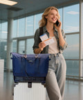 Blue rolling duffle bag atop a white suitcase in an airport terminal.