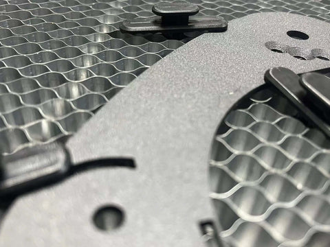 Front view of grey honeycomb laser bed with a black fixing pin clip and hex grid