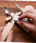 Top Shelf Steel Carving Knife Set Featuring Three Razor Drawknives And Heavy Duty Chisels, user sharpening blade on wooden desk.