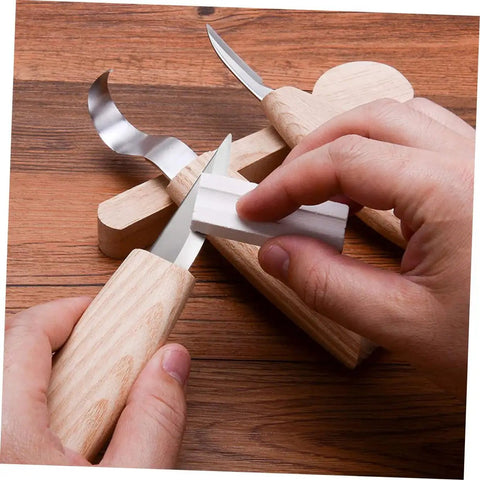 Top Shelf Steel Carving Knife Set Featuring Three Razor Drawknives And Heavy Duty Chisels, user sharpening blade on wooden desk.