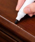 Deliver A No Sweat Slick Finish With This Elite Furniture Fix Kit Featuring Three Premium Wood Touch Up Markers In Rich Black Cherry Walnut Tones To Knock Out Stubborn Scratches And Freshen Up Floors Or Cabinets Fast. A hand using a black touch up marker on furniture.