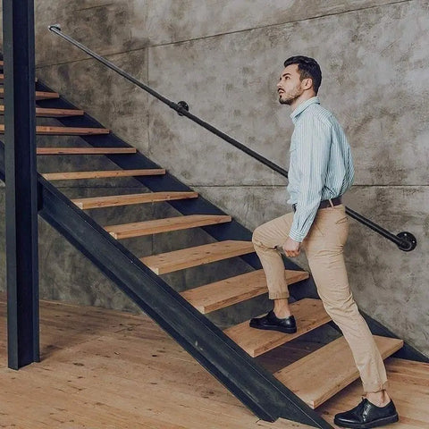 Man using Rock Solid Matte Black Industrial Pipe Stair Handrail Wall Mounted Safety Railing while climbing stairs.
