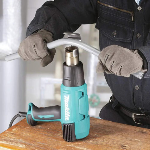 Worker using Versatile Variable Temperature Heat Gun Kit With LCD Display 122 To 1202 F Control And 3 Air Flow Settings for bending metal.
