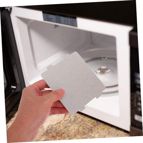 Hand installing microwave waveguide covers mica sheets for heat resistance in home oven, universal fit insulation board, easy to cut.