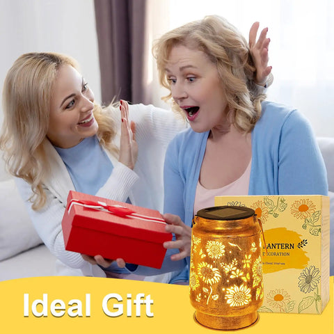 Two women exchanging gift with Solar Lanterns Outdoor Hanging Lights Waterproof For Yard Patio Porch Garden LED Decoration With Shepherd Hook Sunflower Pattern Cozy Warm Glow For Nighttime Ambiance Perfect Gift For Women Mom Grandma.