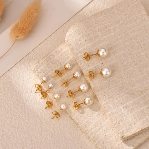 Five Piece Pearl Stud Earrings Set With Gold Finish Ball Studs From 4mm To 8mm For Women And Men, Classic Gold Pearl Earrings For Everyday Wear, Dope For Multiple Piercings And Modern Day Style. Gold pearl stud set on stone backdrop
