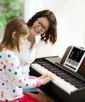 Child playing 61 Key Starter Keyboard Piano With Classic Wooden Frame Electric Digital Piano Sustain Pedal Music Stand USB MP3 Audio Mic and Headphone Support Kid Friendly Gift For Girls Daughter Birthday while adult watches.