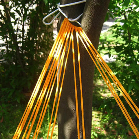 Close-up of vibrant orange outdoor nylon rope hammock swing attached to tree, mesh seat visible.
