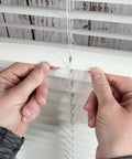 Hands applying Clear Mini Slat Repair Kit to mend cracked horizontal blinds, showcasing easy DIY fix for window coverings.