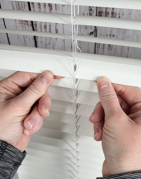 Hands applying Clear Mini Slat Repair Kit to mend cracked horizontal blinds, showcasing easy DIY fix for window coverings.