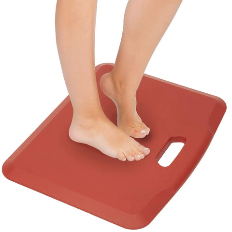 Feet standing on a red 18x22 inch Anti Fatigue Standing Desk Floor Mat For Home Office Kitchen Garage, cushioned and non-slip surface.
